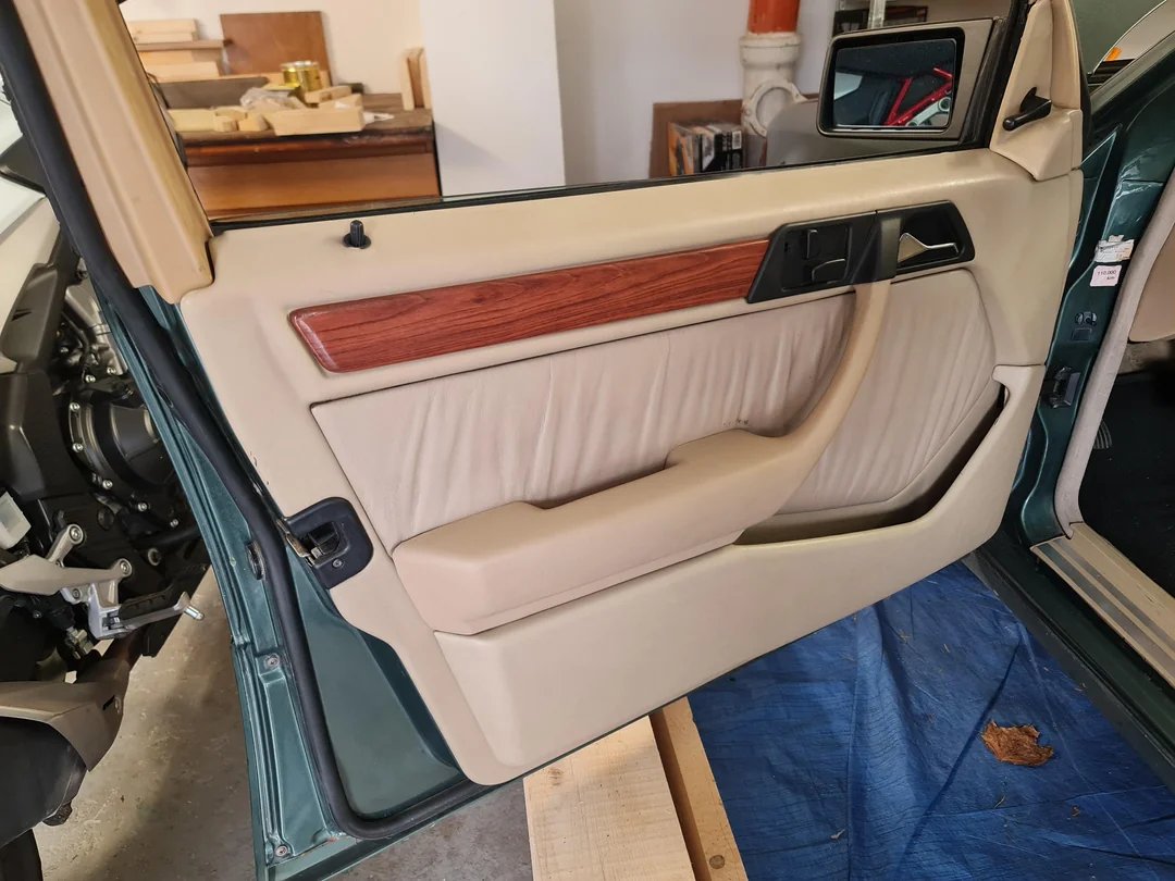 The finished wood trim fitted on the W124 front door panel